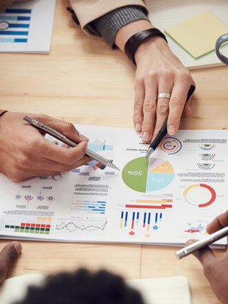 Business team reviewing printed analytics report with charts and graphs on a desk, discussing data insights and performance strategy during a collaborative meeting.